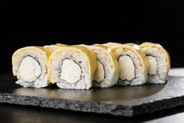 Sushi Rolls with processed cheese, cheddar, american cheese and Cream Cheese inside on black slate isolated. Philadelphia roll sushi with shrimp. Sushi menu. Horizontal photo.