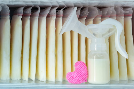 Stock Of Breast Milk Frozen In Storage Bags And A Pump Bottle For A New Baby Of Family And Pink Heart With Love In The Freezer Of Refrigerator.