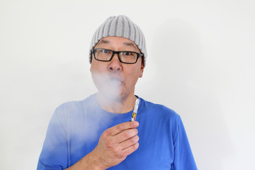 An Asian man enjoying smoking with a vape pen.