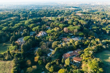 Aerial view of ancient Via Appia Antica with green trees, meadows, houses and pathways in Rome, Italy.