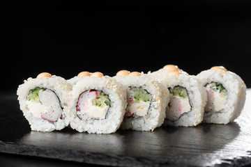 Sushi Rolls with shrimp , cucumber and cream cheese inside on black slate isolated. California rolls covered white sesame seeds. Sushi menu. Horizontal photo.