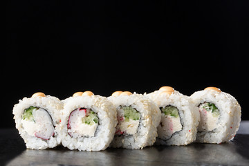 Sushi Rolls with shrimp , cucumber and cream cheese inside on black slate isolated. California rolls covered white sesame seeds. Sushi menu. Horizontal photo.
