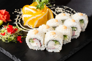 Sushi Rolls with avocado , cucumber, green onion and carrot inside on black slate isolated. Vegan california rolls covered white sesame seeds. Sushi menu. Horizontal photo.