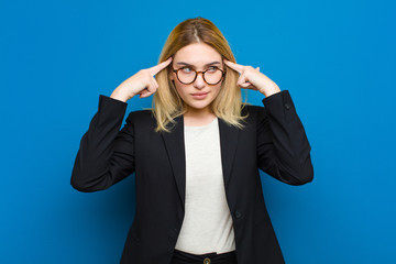 young pretty blonde woman looking concentrated and thinking hard on an idea, imagining a solution...