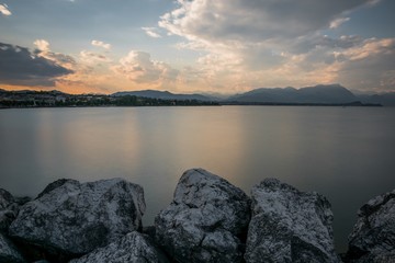 Huge rocks near the lake Garda with the reflection of the sunset sky in Italy