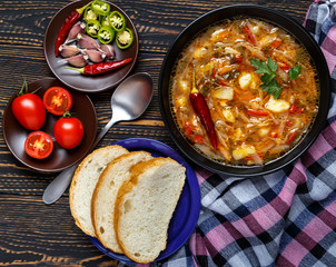 Vegetable soup with tomatoes and chili peppers. Borsch is a national Ukrainian dish. The concept of vegetarian food. Black plate with soup on a black wooden background