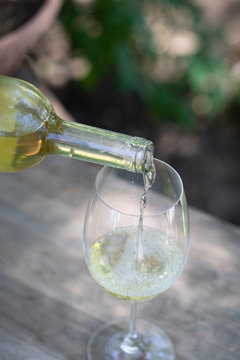 White wine being poured into glass outdoors