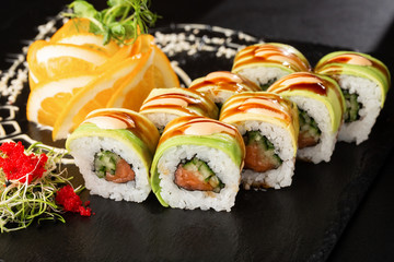 Green dragon sushi roll with salmon, cucumber and avocado. Japanese food. Traditional asian rice sushi healthy seafood. Black background. Horizontal photo.