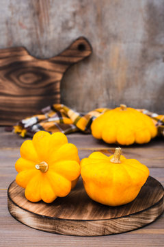 Three fresh bush pumpkin on a cutting board on wooden background