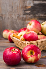 Fresh harvest of apples. Nature theme with red apples in a basket on a wooden background. Fruit nature concept.