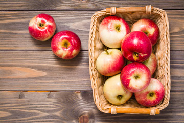 Fresh harvest of apples. Nature theme with red apples in a basket on a wooden background. Fruit nature concept. Top view