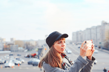 girl taking pictures on a phone on a city street
