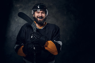 Happy toothless hockey player is posing for photographer with hockey stick.