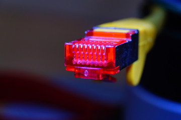 Macro cross section angle view of yellow RJ45 CAT6 shielded network data internet cable red connector on dark background