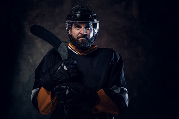 Serious pensive hockey player has a photo session at photo studio.