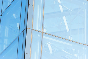 Glass transparent windows on the facade of a modern high-rise office or commercial building in the center of a big city reflect the blue sky