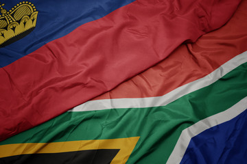 waving colorful flag of south africa and national flag of liechtenstein.