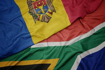 waving colorful flag of south africa and national flag of moldova.