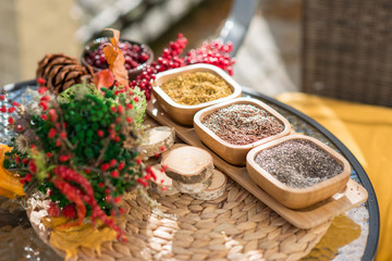 Spices in wooden bowls with autumn decorations on the wooden table