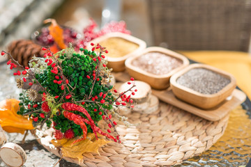 Spices in wooden bowls with autumn decorations on the wooden table