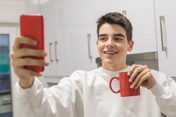 young man at home with cup making photo with smartphone