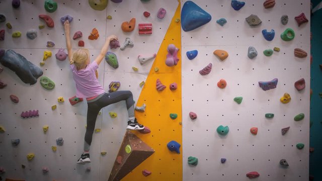 7 year old girl training on climbing gym wall. Slow motion, 4K UHD.