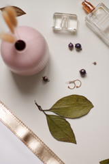 on a light background decoration earrings with beads and beads pink vase and perfume fashion.