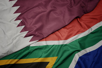 waving colorful flag of south africa and national flag of qatar.