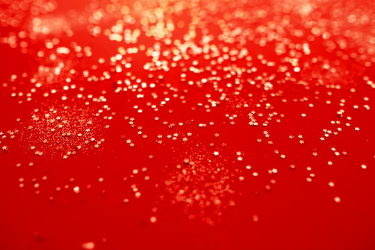 Gold sparkles and stars on red background, christmas concept.