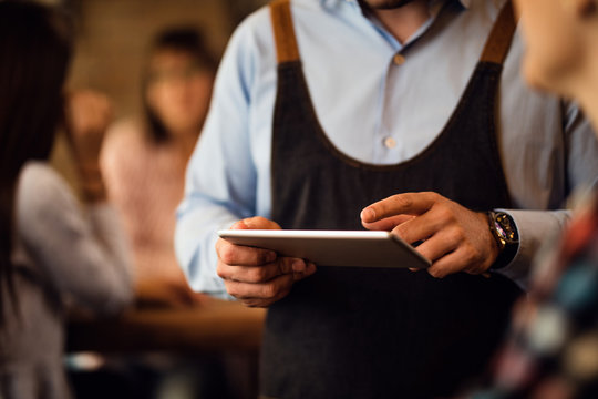 Close-up of waiter writing order on digital tablet in a pub.