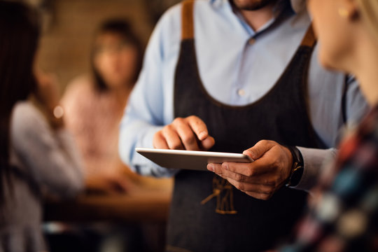 Close-up of unrecognizable waiter using touchpad in a bar.