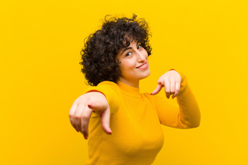 young pretty afro woman feeling happy and confident, pointing to camera with both hands and...