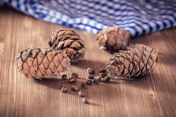 Pine nuts on a wooden table next to the cones