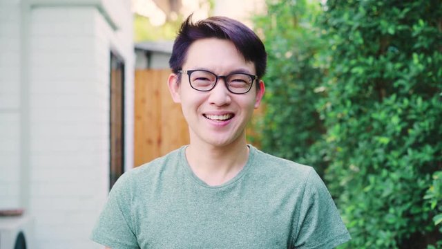 Portrait Asian Chinese man feeling happy smiling at house. Young friendly male relax toothy smile looking to camera while standing in the garden at home in the morning concept.