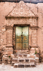 Fototapeta na wymiar Entrance door of a clay house with decoration in relief on a street of Juli city, Puno region, Peru
