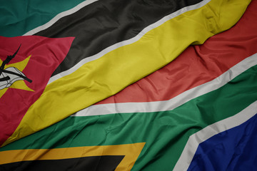 waving colorful flag of south africa and national flag of mozambique.