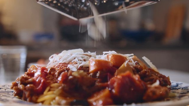 Close Up Of Fresh Italian Parmesan Cheese Being Grated On Top Of Hot Steamy Spaghetti With Bolognese Sauce