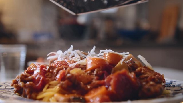 Close Up Of Fresh Italian Parmesan Cheese Being Grated On Top Of Hot Steamy Spaghetti With Bolognese Sauce