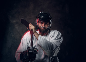 Bearded brutal hockey player is posing for photographer and red light is creating effect of movement.