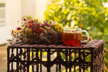 Cup of herbal tea beside dried flower bouquet on garden table