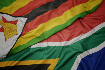 waving colorful flag of south africa and national flag of zimbabwe.