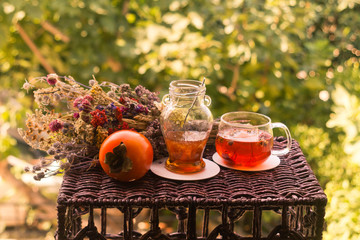 Cup of tea, jar of jam, persimmon fruit and dried flower bunch