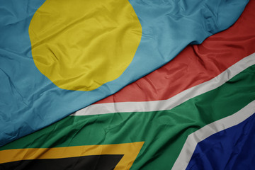 waving colorful flag of south africa and national flag of Palau .