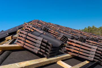 Roof ceramic tile arranged in packets on the roof on roof battens. Preparation for laying roof tiles.