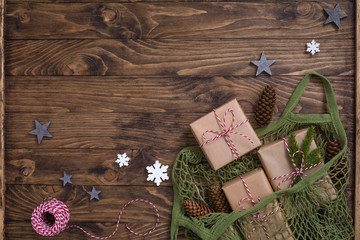 New Year Christmas composition with net bag with fir tree branches, presents, cones on wooden background