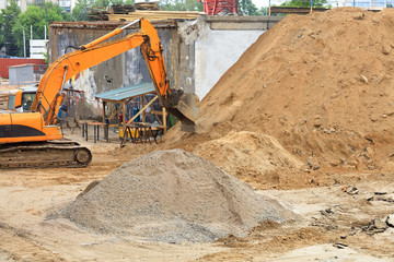 Heavy construction excavator during the construction of a road and a new multi-storey building.