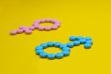 Blue pills in the form of a gender signs of Mars and Venus on a yellow background. Medical concept.