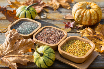 Spices in wooden bowls with autumn decorations on the wooden table