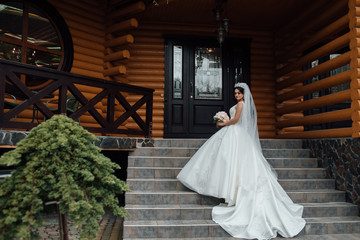 Beautiful bride in luxurious ballroom dress walking up the stairs with beautiful bouquet. Beautiful...