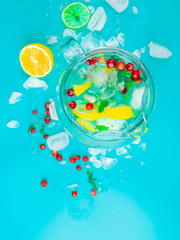 Refreshing lemon water in glass jug with ice cubes on blue background